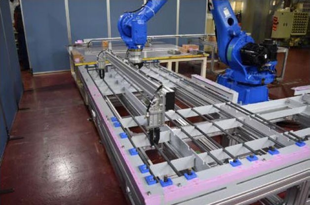 鉄筋自動組み立てシステム「Robotaras」の試作機。<br>ロボットアームの先端部に鉄筋保持治具を取り付け、鉄筋を型枠内に配置しているところ